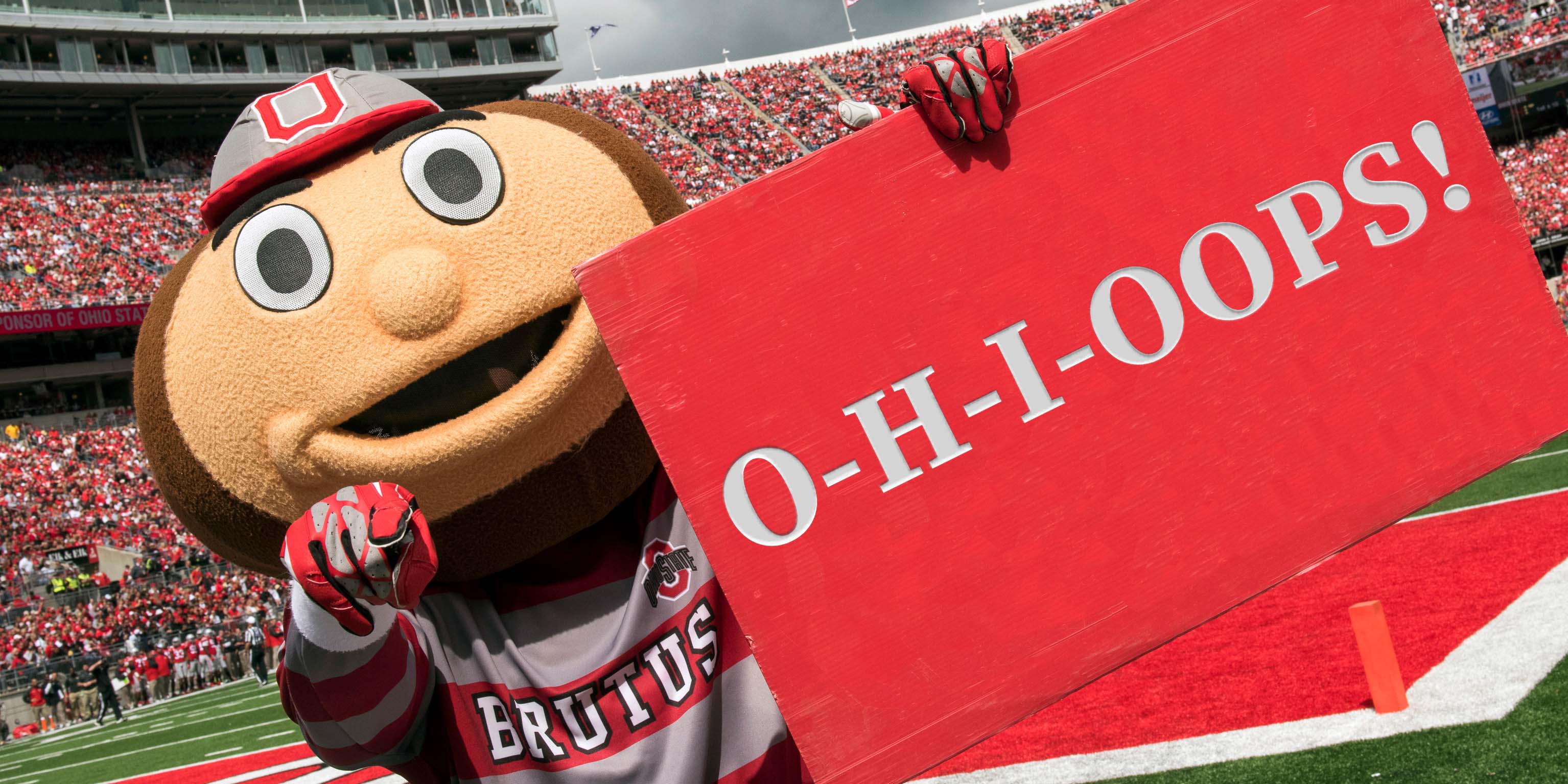 Brutus Buckeye holding a sign saying "O-H-I-Oops"